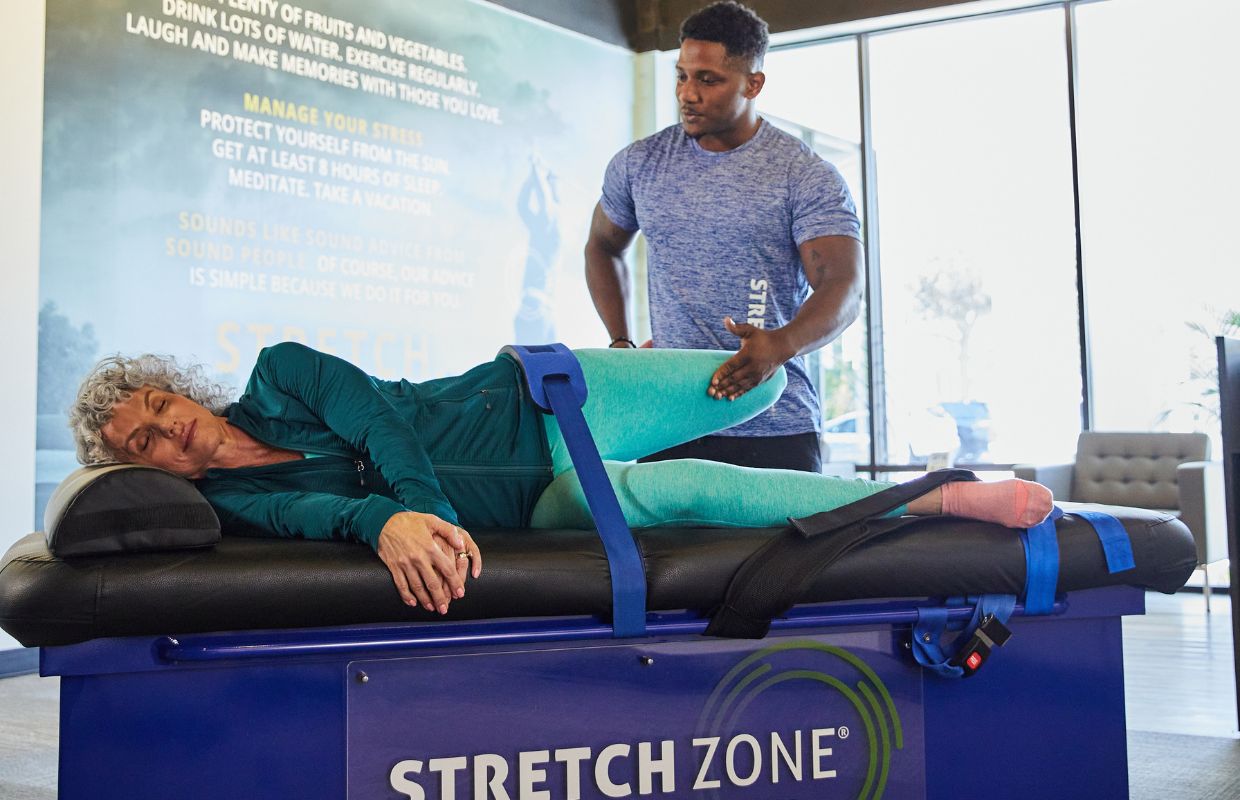 Stretch practitioner performing a quad stretch on a client at a Stretch Zone studio