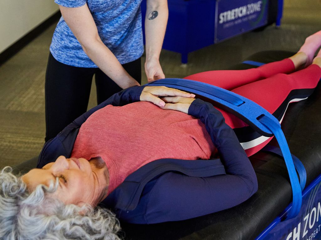 Stretch Practitioner adjusting straps on client at a Stretch Zone studio