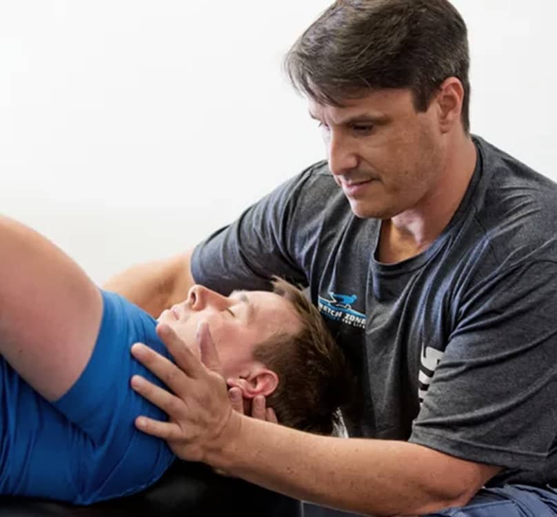 Image of a person doing stretching exercises with the assistance of a professional trainer.