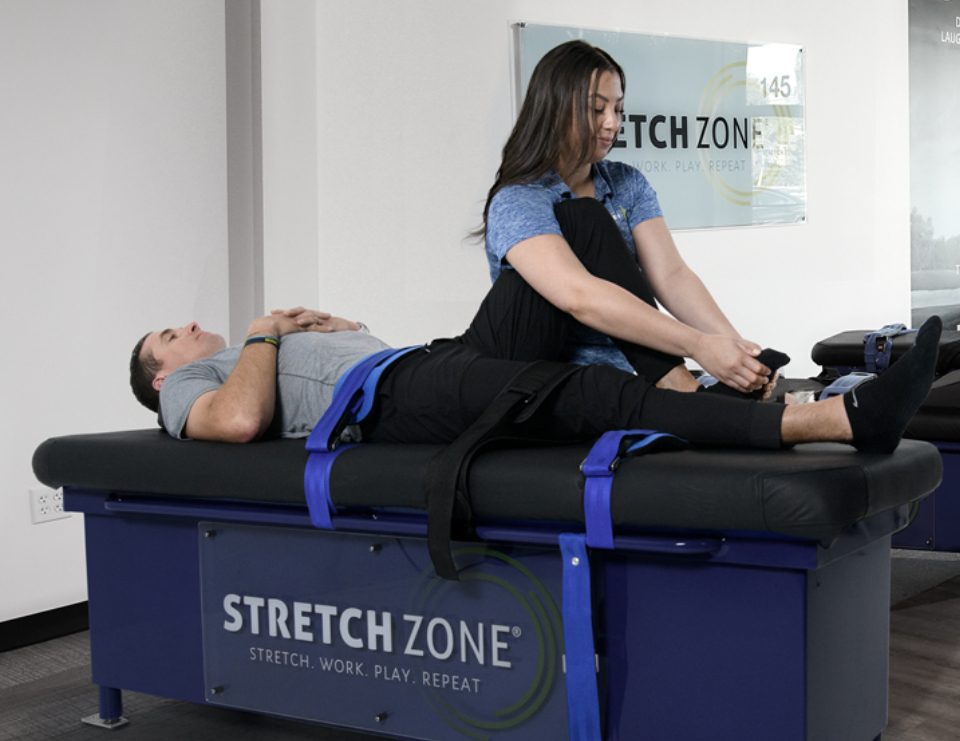 Experienced fitness trainer guiding a client through a personalized stretching routine at Stretch Zone studio