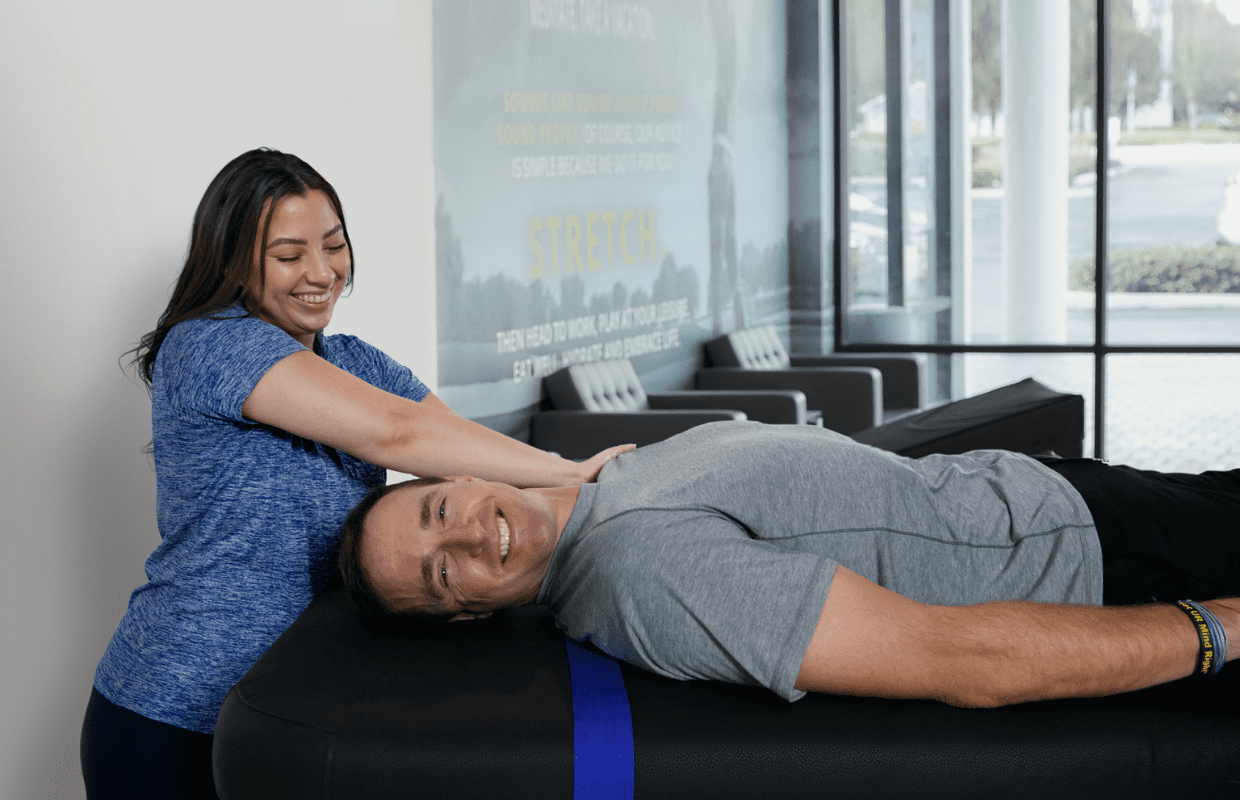 Experienced fitness trainer guiding a client through a personalized stretching routine at Stretch Zone studio