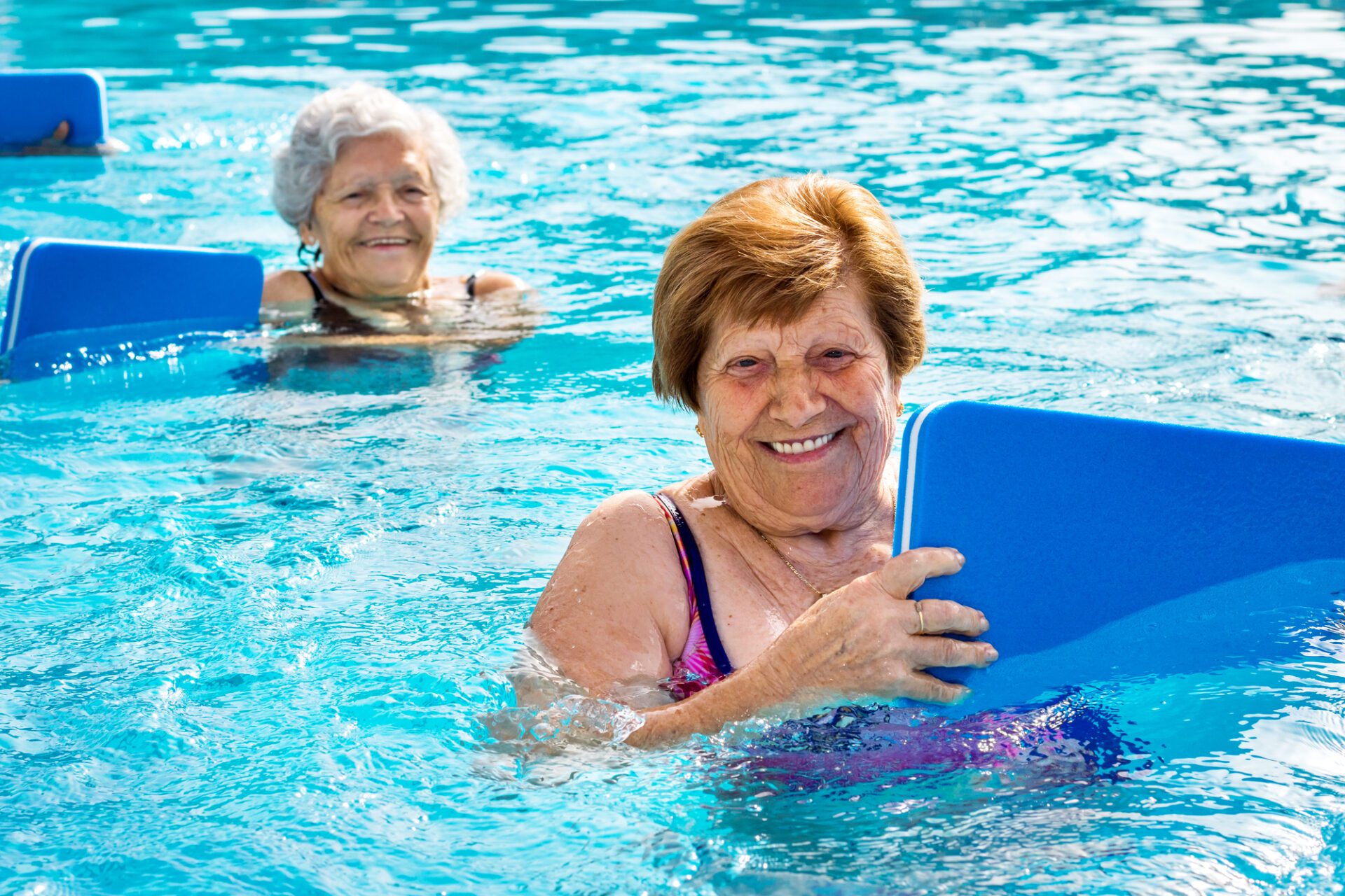 Senior women doing aqua exercise with kick boards.