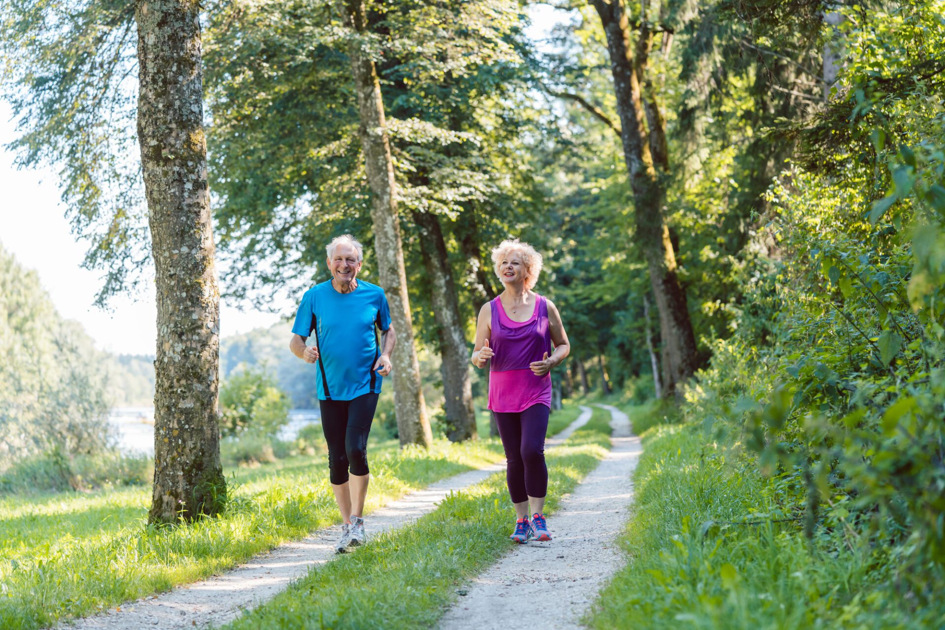 Two active seniors with a healthy lifestyle smiling while jogging