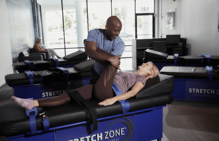 Experienced fitness trainer guiding a client through a personalized stretching routine at Stretch Zone studio