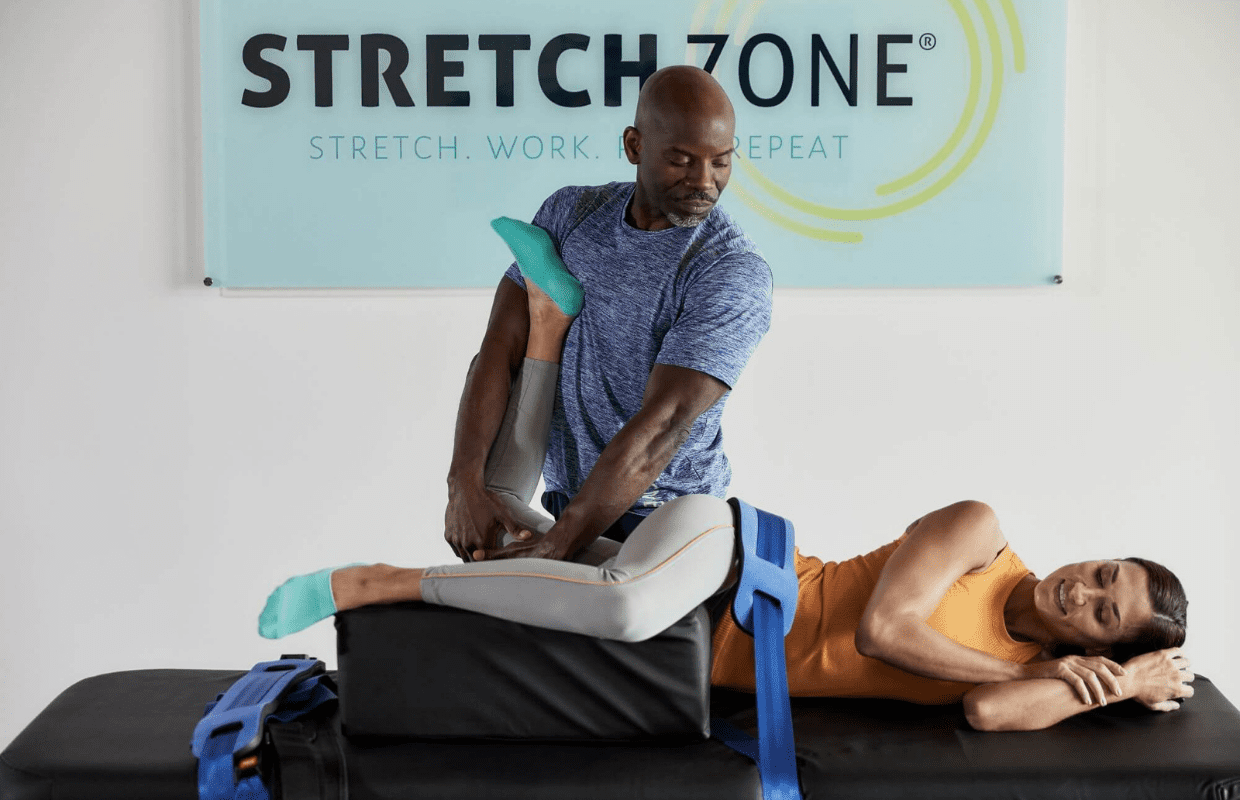 Experienced fitness trainer guiding a client through a personalized stretching routine at Stretch Zone studio