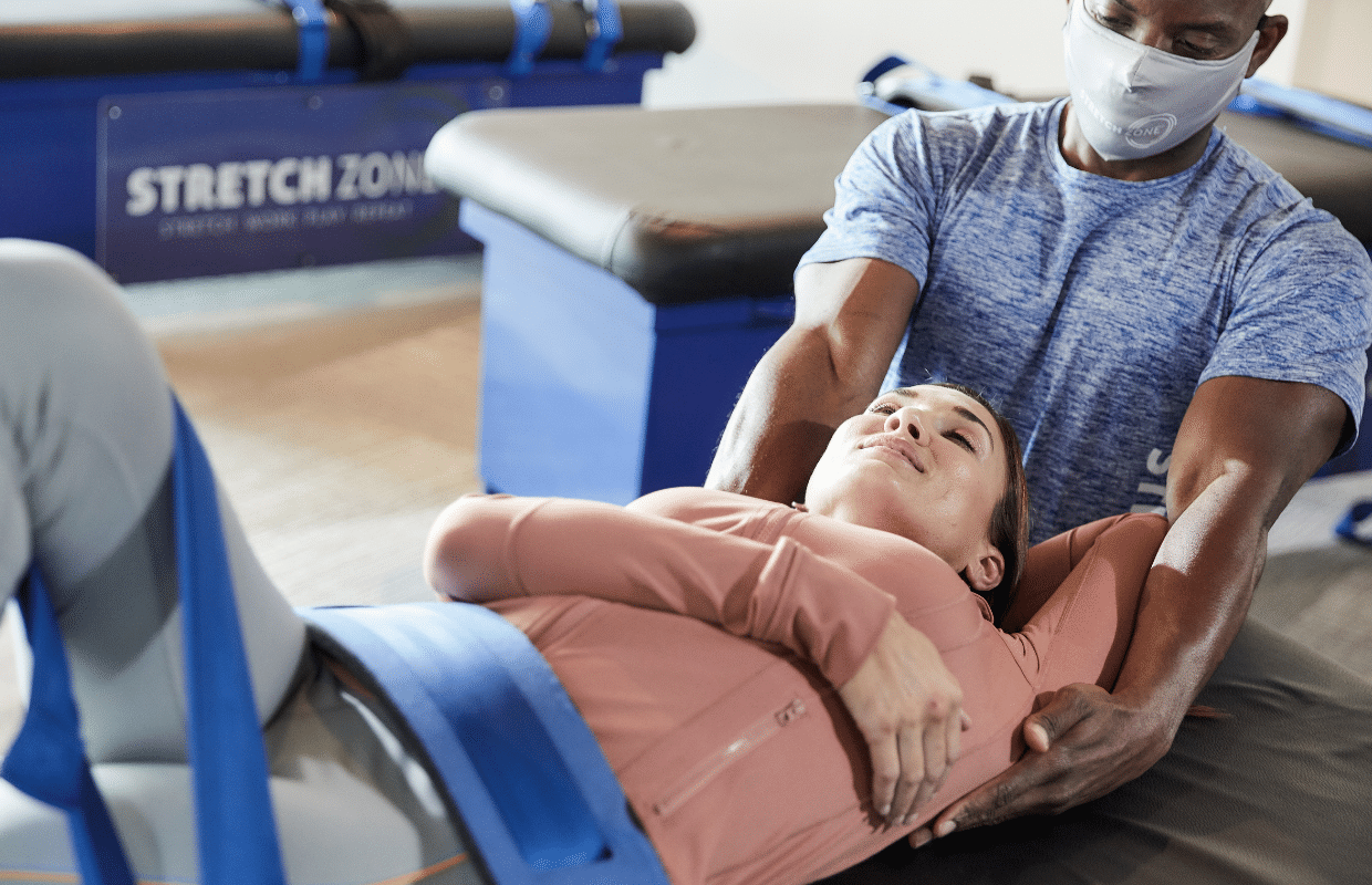 Experienced fitness trainer guiding a client through a personalized stretching routine at Stretch Zone studio