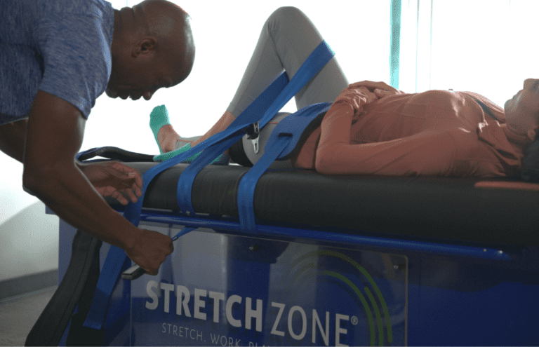 Experienced fitness trainer guiding a client through a personalized stretching routine at Stretch Zone studio