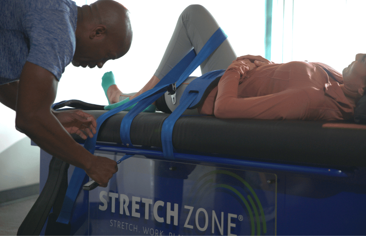 Experienced fitness trainer guiding a client through a personalized stretching routine at Stretch Zone studio