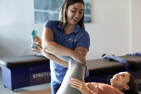 Experienced fitness trainer guiding a client through a personalized stretching routine at Stretch Zone studio