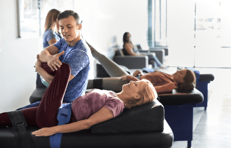 Experienced fitness trainer guiding a client through a personalized stretching routine at Stretch Zone studio