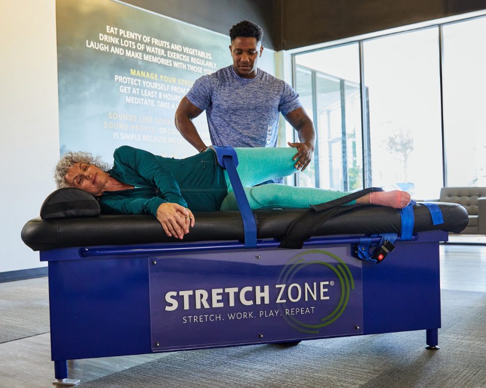 Experienced fitness trainer guiding a client through a personalized stretching routine at Stretch Zone studio