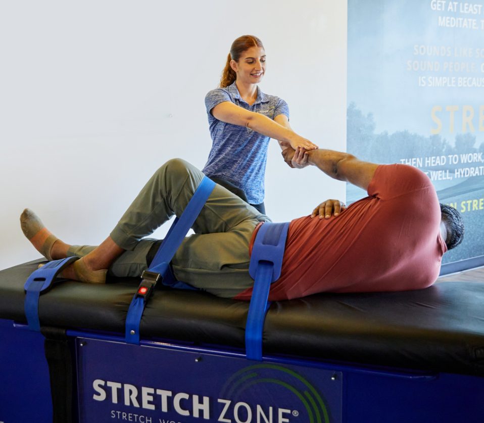 Experienced fitness trainer guiding a client through a personalized stretching routine at Stretch Zone studio