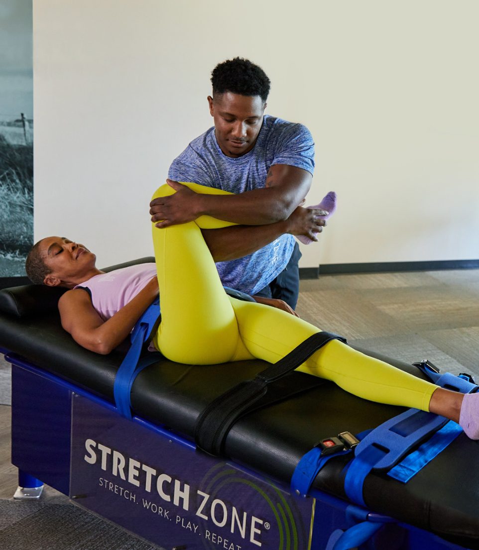 Experienced fitness trainer guiding a client through a personalized stretching routine at Stretch Zone studio