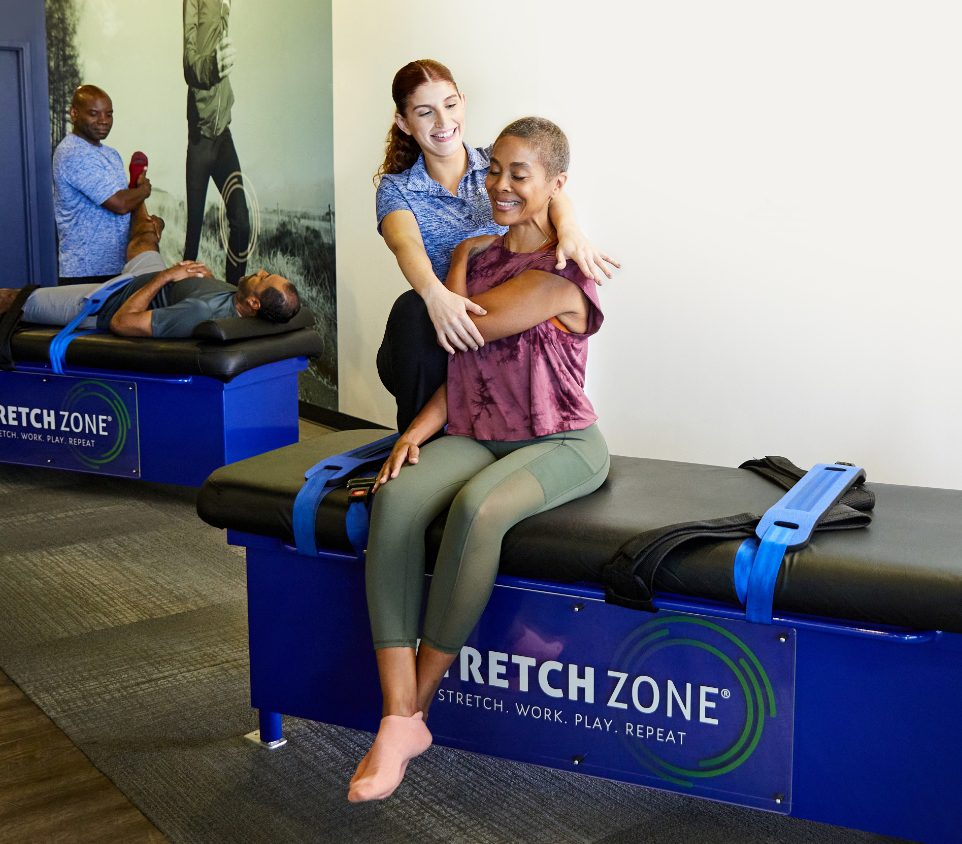 Experienced fitness trainer guiding a client through a personalized stretching routine at Stretch Zone studio