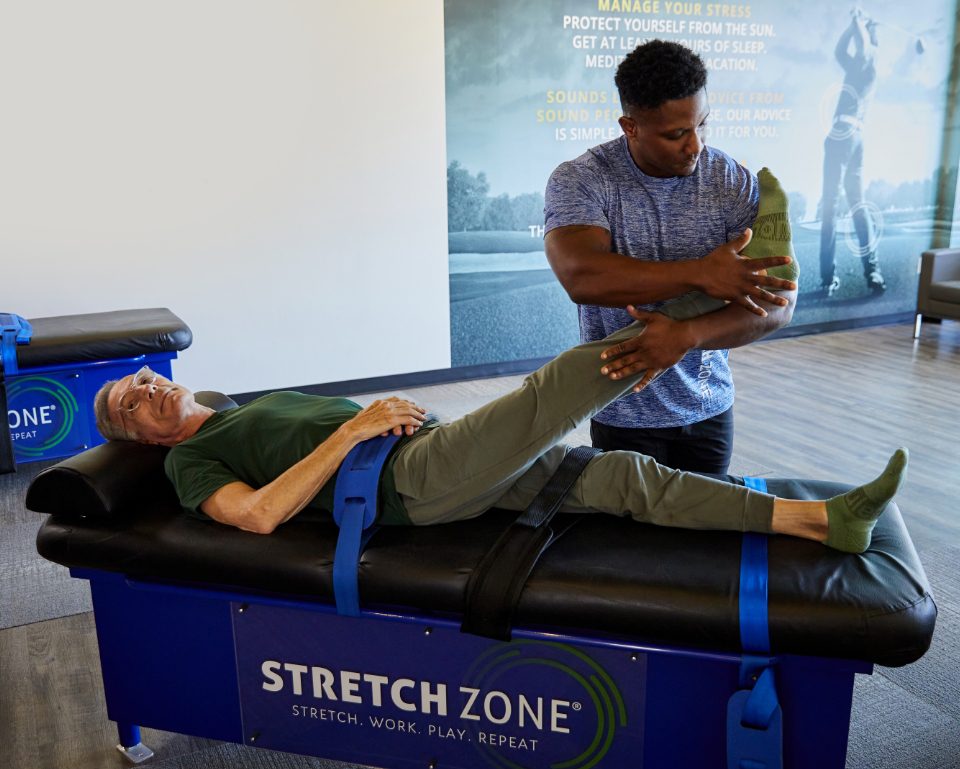 Experienced fitness trainer guiding a client through a personalized stretching routine at Stretch Zone studio