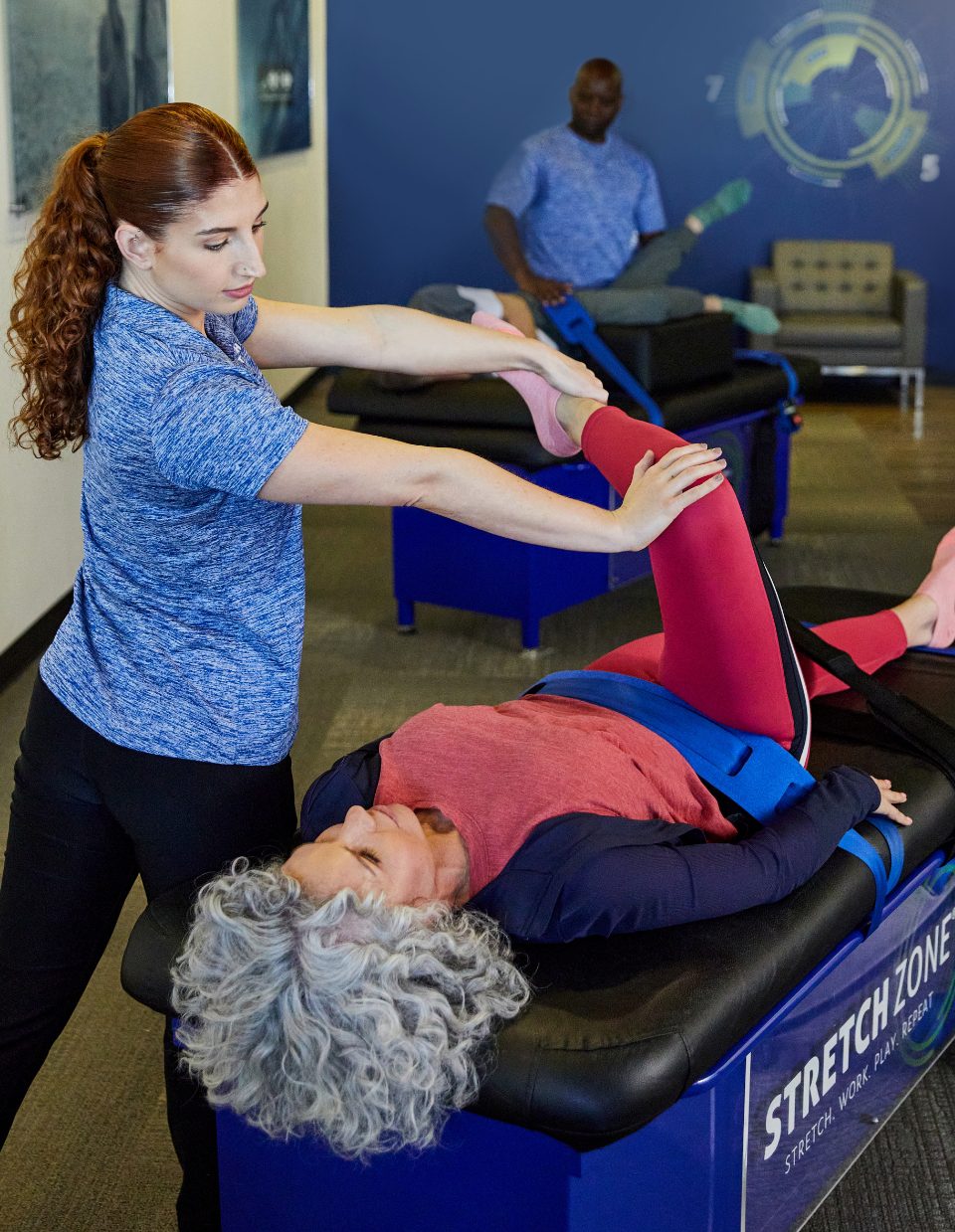 Experienced fitness trainer guiding a client through a personalized stretching routine at Stretch Zone studio