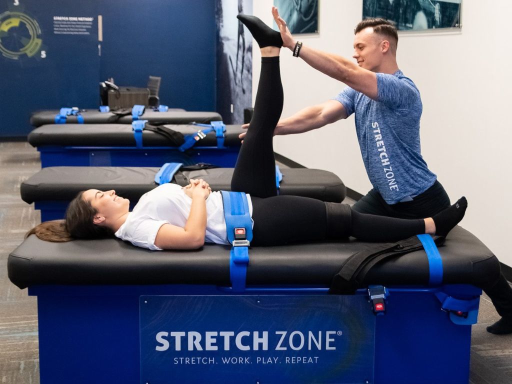 Stretch practitioner performing a hamstring stretch on a client at a Stretch Zone studio.