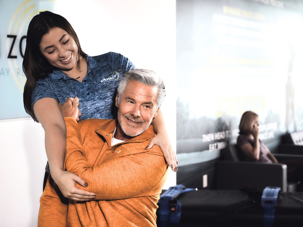 Stretch practitioner performing shoulder stretch on a client at a Stretch Zone studio